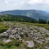 Kamienny szlak i kopczyk na górskim szczycie. W oddali widać zalesione pasma górskie, idealne miejsce na odkrywanie międzylesie atrakcje.