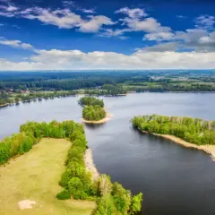 Malownicze polskie wyspy na Bałtyku, otoczone ciemną wodą i bujną zielenią, pod błękitnym niebem z chmurami.