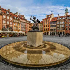 Syrenka Warszawska na Rynku Starego Miasta, sercu warszawskich dzielnic, z kolorowymi kamienicami w tle.
