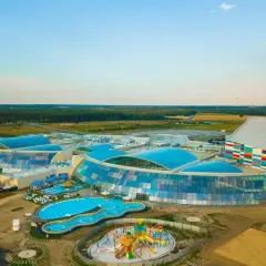 Nowoczesny park wodny Suntago z przeszklonymi dachami i kolorową fasadą, otoczony zielenią.