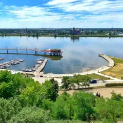 Nowoczesna marina i promenada nad rzeką, z widokiem na miasto. To jedne z wielu **ciekawych miejsc na Mazowszu**, idealnych na letni wypoczynek.