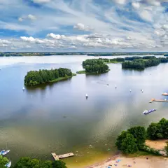 Idealne wakacje nad wodą: żaglówki, wyspy porośnięte drzewami i plażowicze cieszący się słońcem.