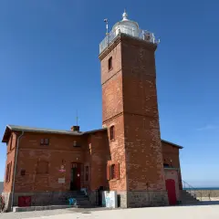 Latarnia morska w Darłowie, jedna z głównych atrakcji, góruje nad ceglanym budynkiem.
