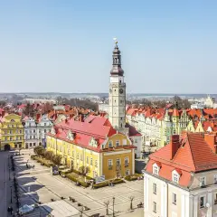Rynek w Bolesławcu z ratuszem i wieżą zegarową. Kolorowe kamienice i brukowany plac tworzą urokliwe bolesławiec atrakcje.