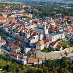 Widok z lotu ptaka na urokliwe miasto Bystrzyca Kłodzka z charakterystycznymi czerwonymi dachami i zabytkową architekturą.