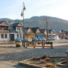 Urokliwy rynek z brukowaną nawierzchnią, kolorowe domki i góry w tle tworzą atmosferę małej Grecji.