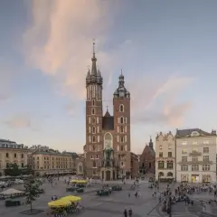 Majestatyczny kościół Mariacki na Rynku Głównym w Krakowie, otoczony kamienicami i placem tętniącym życiem.
