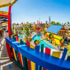 Kolorowy park rozrywki w Małopolsce, z wodną atrakcją i budynkami w kształcie zabawek.