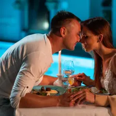 Romantyczna kolacja przy basenie, idealne fajne miejsca na sylwestra we dwoje. Para trzyma się za ręce, patrząc sobie w oczy.