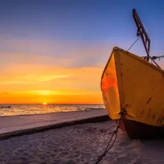 Żółta łódź na plaży w Niechorzu podczas zachodu słońca. Piękne niechorze atrakcje czekają na odkrycie.