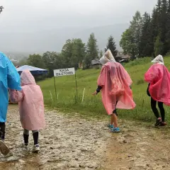 Rodzina w kolorowych pelerynach idzie błotnistą ścieżką. Nawet gdy pada deszcz, w Zakopanem można znaleźć ciekawe atrakcje.