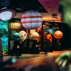 Interaktywne muzeum w Warszawie prezentuje modele planet. Widać Jowisza, Marsa i Ziemię, a także Saturna z pierścieniami.