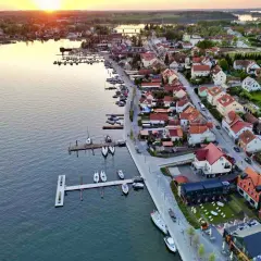 Zachód słońca nad jeziorem w Mikołajkach. Widok na port z łodziami i urokliwe miasteczko z czerwonymi dachami. Idealne miejsce na wakacyjne mikołajki atrakcje.