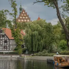Urokliwe zakątki Kujaw i Pomorza: zabytkowa zabudowa, malownicza rzeka i łódź spacerowa. Odkryj atrakcje regionu!