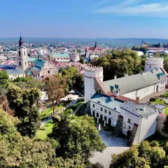 Zamek w Sandomierzu i miasto z wieżą kościelną. Warto przemyśl atrakcje tego miejsca, spacerując po zielonych terenach.