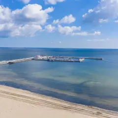 Molo z jachtami i żaglówkami, idealne atrakcje nad morzem. Piękny dzień, błękitne niebo i spokojne morze.