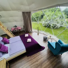Przytulne wnętrze namiotu sferycznego z wygodnym łóżkiem i widokiem na zieleń. Idealne miejsce na glamping w Nałęczowie.