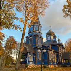 Jesienna odsłona cerkwi na Podlasiu. Złote liście i błękitne niebo podkreślają piękno drewnianej architektury, tworząc malownicze podlaskie atrakcje.