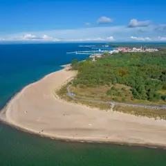 Piękna plaża i las na Helu. W oddali widać miasteczko i port. Idealne miejsce na wakacyjne atrakcje.