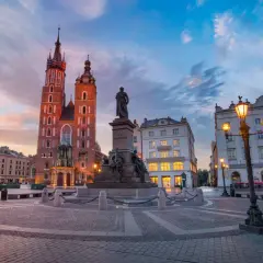 Kraków co zwiedzić? Rynek Główny z Kościołem Mariackim i pomnikiem Mickiewicza o zachodzie słońca. Idealne miejsce na spacer.