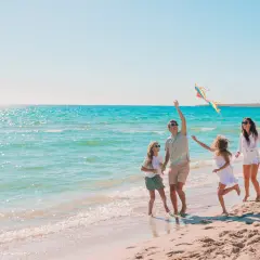 Rodzina z dziećmi puszcza latawiec na plaży. Idealne miejsce, gdzie nad morze z niemowlakiem, by cieszyć się słońcem i falą.