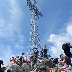 Tłum turystów na skalistym szczycie pod krzyżem, gdzie jest Giewont.