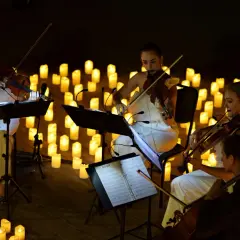 Nastrojowy koncert przy świecach w Poznaniu. Kobiety grają na skrzypcach w otoczeniu setek płonących świec.
