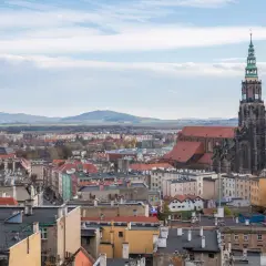 Widok na miasto z dominującą wieżą kościoła. W oddali góry. **Świdnica atrakcje** zachwycają.