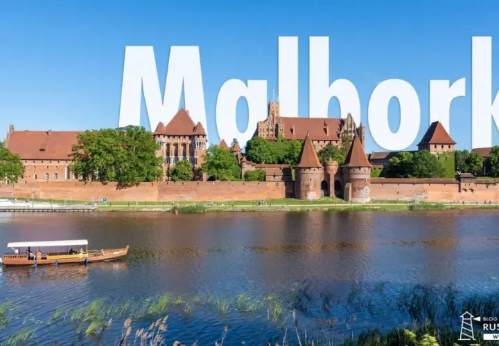 Malbork atrakcje: potężny zamek krzyżacki nad rzeką, z łodzią turystyczną na pierwszym planie.