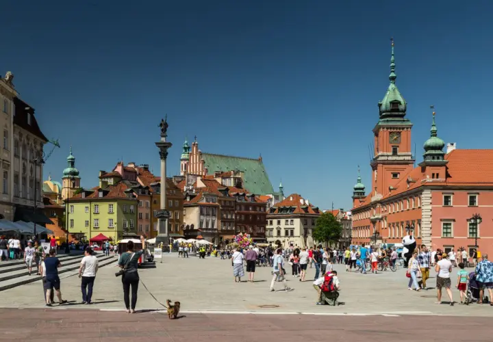 Warszawski Rynek Starego Miasta tętni życiem. Widać tu wiele zabytków w Polsce, w tym Zamek Królewski i Kolumnę Zygmunta.