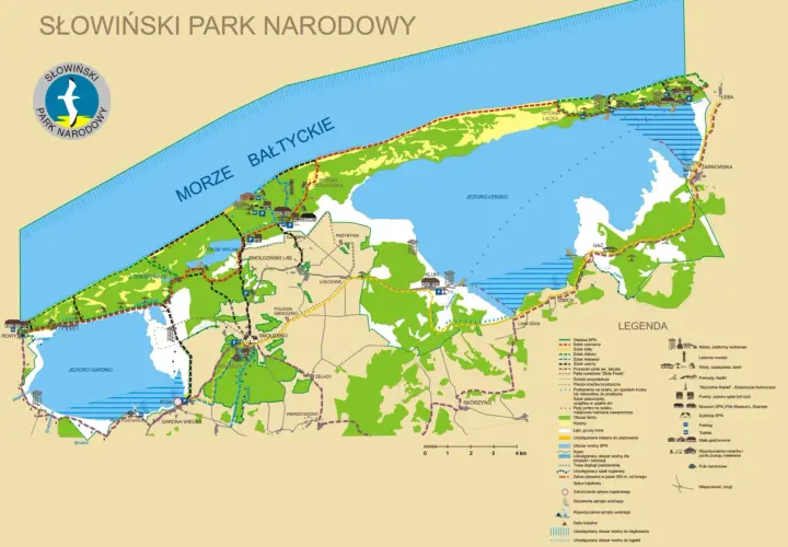 Mapa turystyczna Słowińskiego Parku Narodowego z zaznaczonymi szlakami, jeziorami, wydmami i miejscowościami.