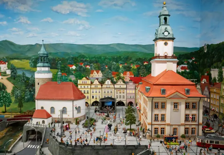 Miniaturowy rynek w Jeleniej Górze, z wieżą ratuszową, kamieniczkami i tłumem ludzi.
