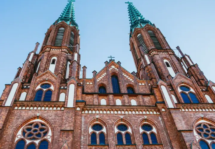 Imponująca ceglana bazylika z dwiema wieżami, ozdobiona oknami i krzyżami. Jeden z najpiękniejszych kościołów w Polsce.