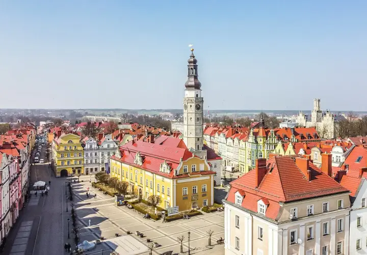 Rynek w Bolesławcu z ratuszem i wieżą zegarową. Kolorowe kamienice i brukowany plac tworzą urokliwe bolesławiec atrakcje.