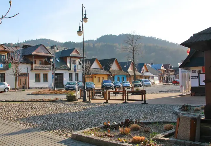Urokliwy rynek z brukowaną nawierzchnią, kolorowe domki i góry w tle tworzą atmosferę małej Grecji.