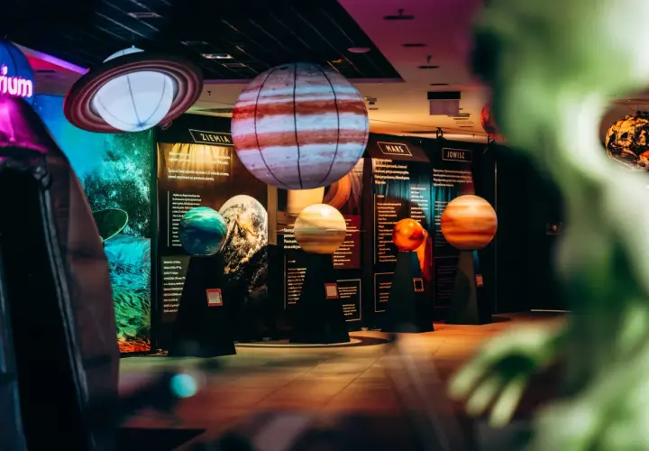 Interaktywne muzeum w Warszawie prezentuje modele planet. Widać Jowisza, Marsa i Ziemię, a także Saturna z pierścieniami.