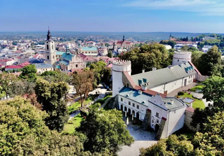 Zamek w Sandomierzu i miasto z wieżą kościelną. Warto przemyśl atrakcje tego miejsca, spacerując po zielonych terenach.