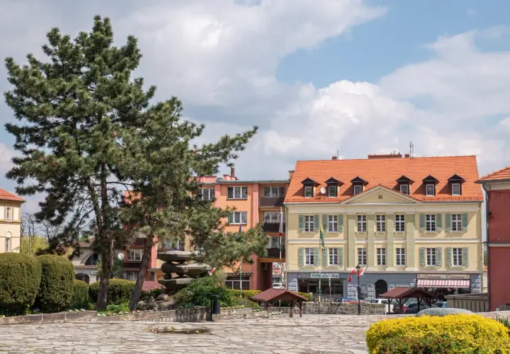 Rynek w Sobótce z kamienną rzeźbą i kolorowymi kamienicami. Idealne miejsce na spacer i odkrywanie lokalnych atrakcji.