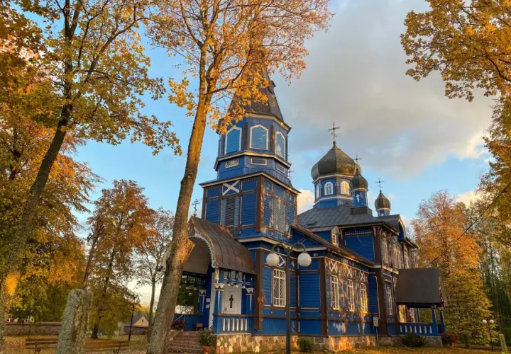 Jesienna odsłona cerkwi na Podlasiu. Złote liście i błękitne niebo podkreślają piękno drewnianej architektury, tworząc malownicze podlaskie atrakcje.