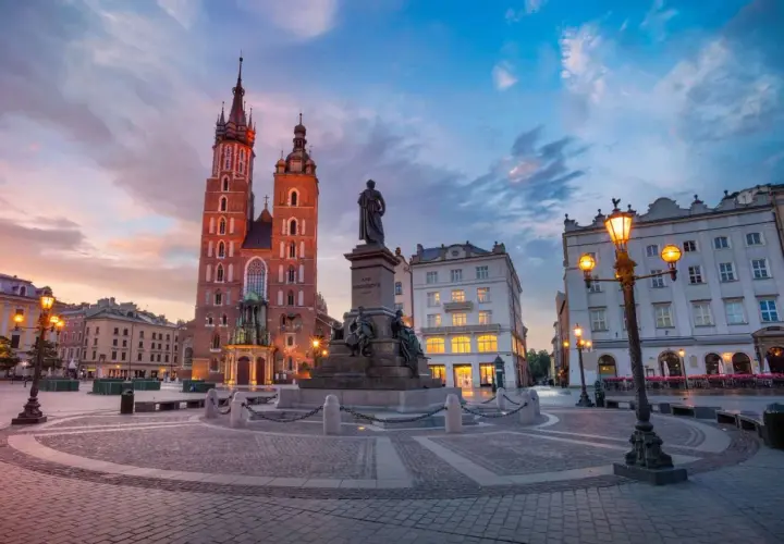 Kraków co zwiedzić? Rynek Główny z Kościołem Mariackim i pomnikiem Mickiewicza o zachodzie słońca. Idealne miejsce na spacer.