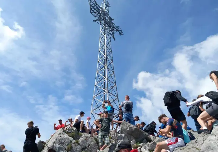 Tłum turystów na skalistym szczycie pod krzyżem, gdzie jest Giewont.