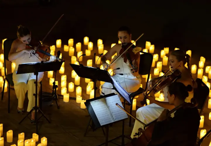 Nastrojowy koncert przy świecach w Poznaniu. Kobiety grają na skrzypcach w otoczeniu setek płonących świec.