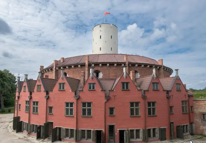 Gdańsk atrakcje dla dorosłych: Twierdza Wisłoujście z charakterystyczną wieżą i ceglanymi budynkami. Idealne miejsce na spacer i odkrywanie historii.