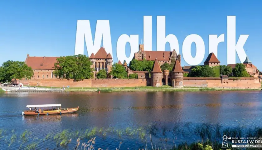 Malbork atrakcje: potężny zamek krzyżacki nad rzeką, z łodzią turystyczną na pierwszym planie.