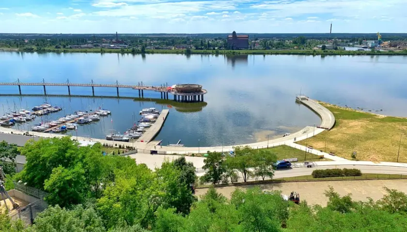 Nowoczesna marina i promenada nad rzeką, z widokiem na miasto. To jedne z wielu **ciekawych miejsc na Mazowszu**, idealnych na letni wypoczynek.