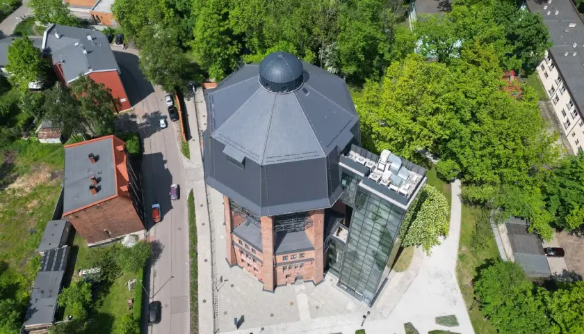 Nowoczesna wieża ciśnień w Zabrzu z przeszkloną windą i tarasem widokowym, otoczona zielenią.