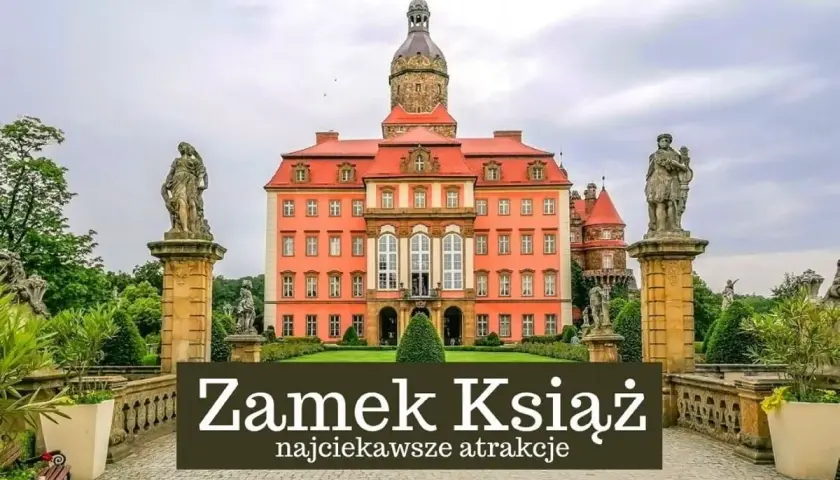 Zamek Książ w Wałbrzychu, imponująca budowla z wieżą i rzeźbami, otoczona zielenią.