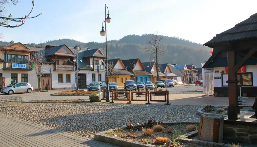 Urokliwy rynek z brukowaną nawierzchnią, kolorowe domki i góry w tle tworzą atmosferę małej Grecji.