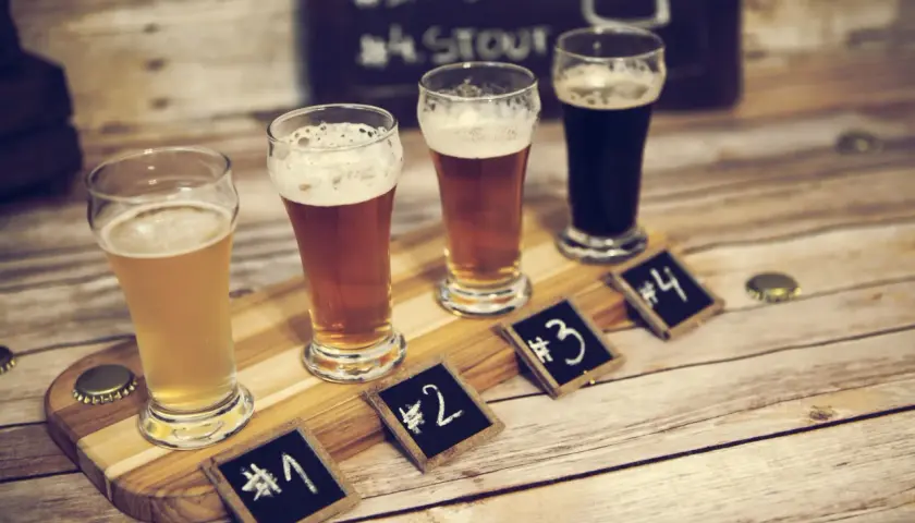 Degustacja piwa w Poznaniu: cztery szklanki z różnymi piwami, oznaczone numerami od 1 do 4, na drewnianej desce.