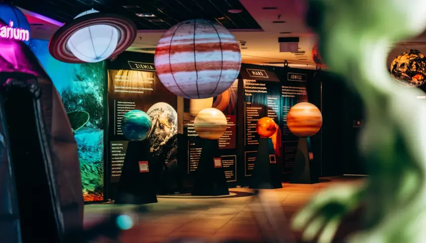 Interaktywne muzeum w Warszawie prezentuje modele planet. Widać Jowisza, Marsa i Ziemię, a także Saturna z pierścieniami.